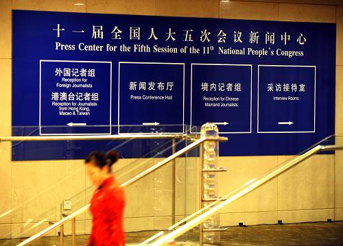 2月26日，一名工作人员从全国两会新闻中心的标识牌旁走过。新华社记者 燕雁 摄
