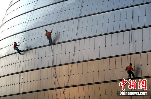 2月26日，北京，几位保洁人员正在对国家大剧院的外壁进行全面清洗，迎接全国“两会”召开。