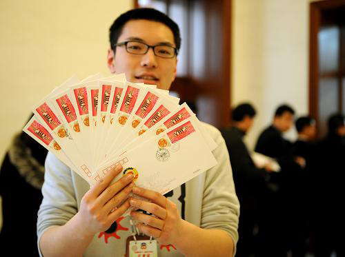3月3日，一位记者在北京人民大会堂展示他买到的全国政协十一届五次会议纪念邮品。当日，全国政协十一届五次会议纪念邮品开始发行。新华社记者 燕雁 摄