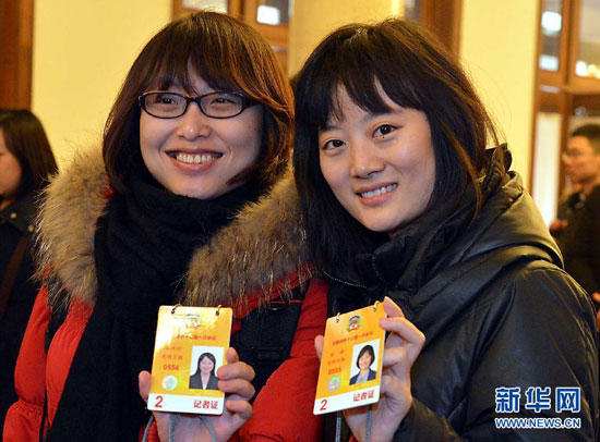 2月28日，两位参加全国政协十二届一次会议采访报道的女记者在全国政协展示刚领到的记者证。 　　新华社记者王颂摄