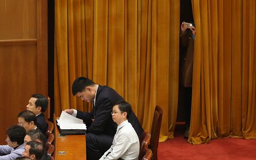  3月3日，中国人民政治协商会议第十二届全国委员会第一次会议在北京人民大会堂开幕。这是一名记者在拍照，她面前是在静静听会的“小巨人”姚明委员。新华社记者 金立旺 摄