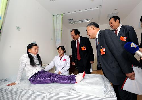 3月9日，全国人大代表张伯礼（前）、赵步长（后右一）和全国政协委员王承德（后右二）在调研中看望接受治疗的小女孩。新华社记者 何俊昌 摄